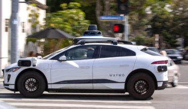 A Waymo autonomous vehicle operating on a tree-lined street in Santa Monica.