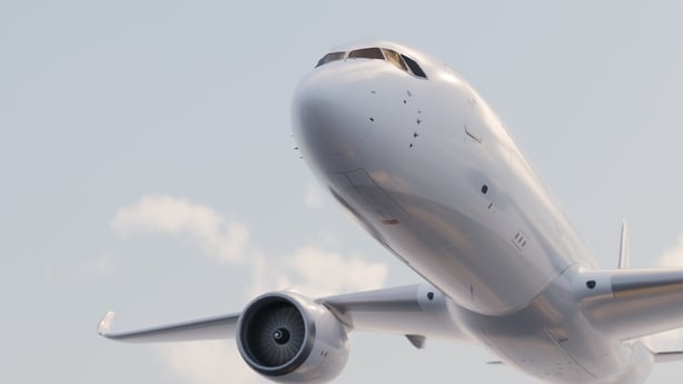 White passenger jet airplane taking off, flying upwards in a blue sky with soft clouds, symbolizing global travel and flight