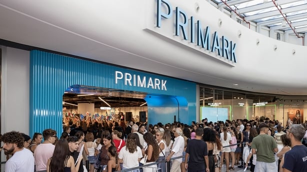 Crowds of people line up outside a shop with Primark branding