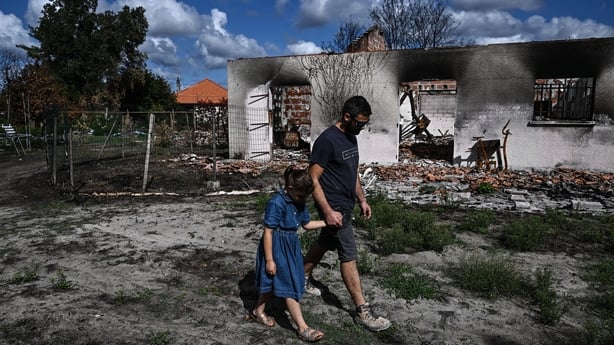 a man and a child walk amid charred landscape after a wildfire