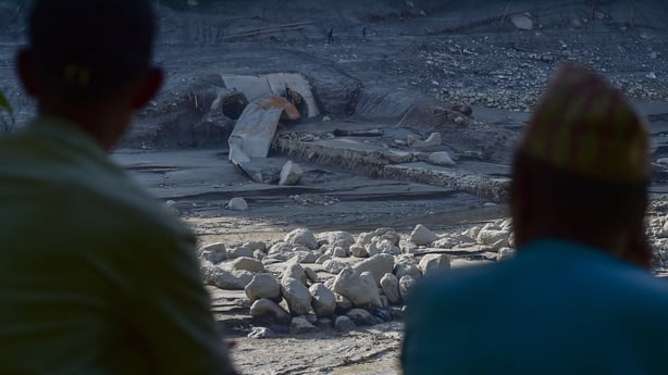 Local residents look at a damaged tunnel of the Trishuli Hydropower Plant on the banks of the swollen Trishuli River.