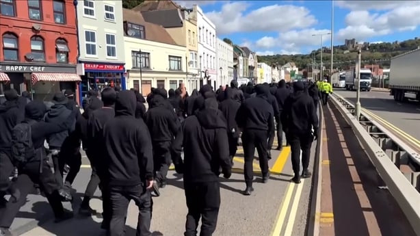 Men dressed all in black walk on road