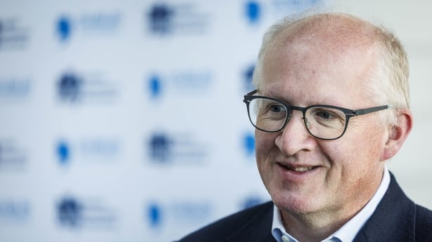 Image of a business man posing for a photo with Dublin Economics Workshop branding in the background