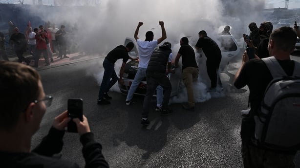 Protesters push a car engulfed in smoke outside the headquarters of the EU Rule of Law Mission (EULEX) in Pristin
