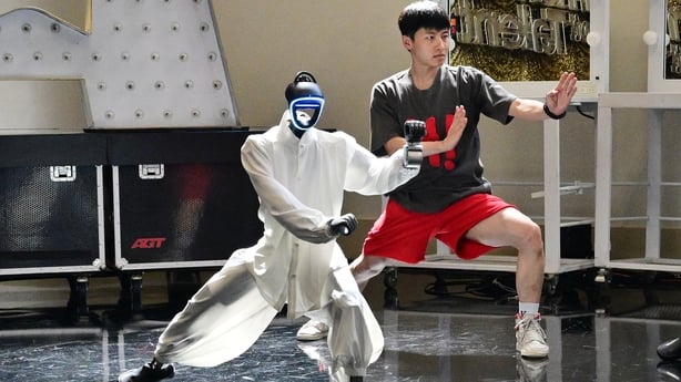 Chinese street dancer Wu Yufei and a Unitree Robotics humanoid robot mimic Tai Chi-like poses during a demonstration in Pasadena, California