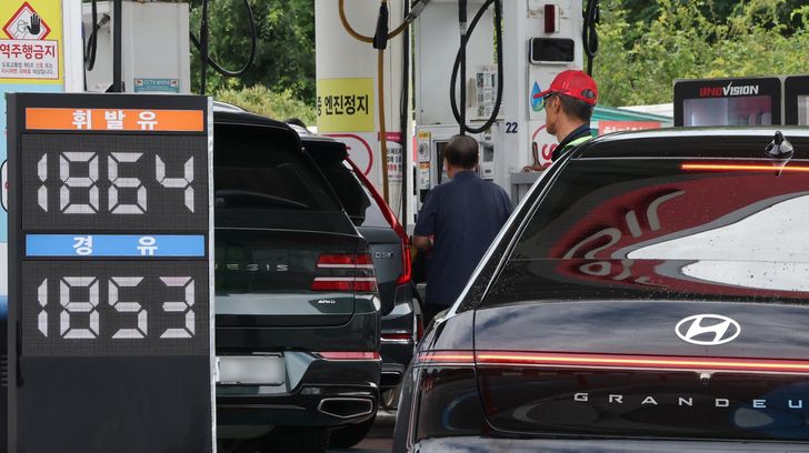 People refuel their cars at a gas station in Seoul, Sunday. Yonhap