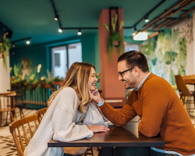 Side view of affectionate happy couple sitting in the cozy cafe. - stock photo
