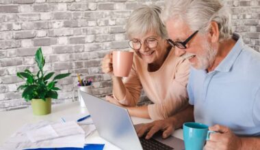 Elderly couple using laptop at home while drinking a cup of coffee.