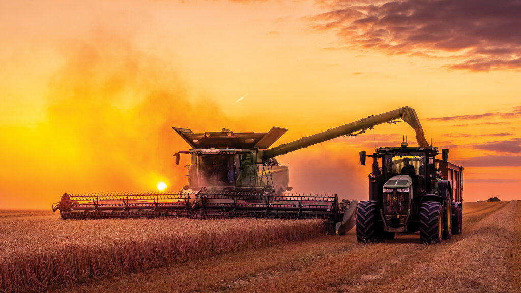 Scenic sunset photo of a John Deere X9 1100 combine working into the night