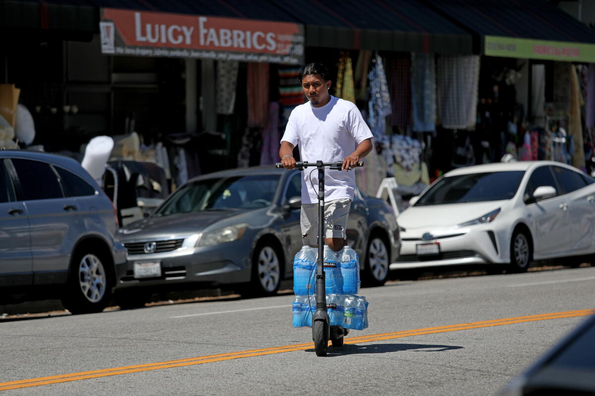 A man hauls water on a scooter in the Fashion District in downtown Los Angeles.