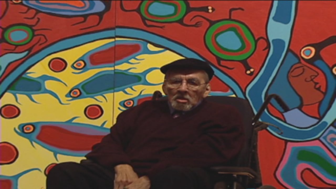 a man in a wheelchair stands before a mural sized painting with vivid colours.