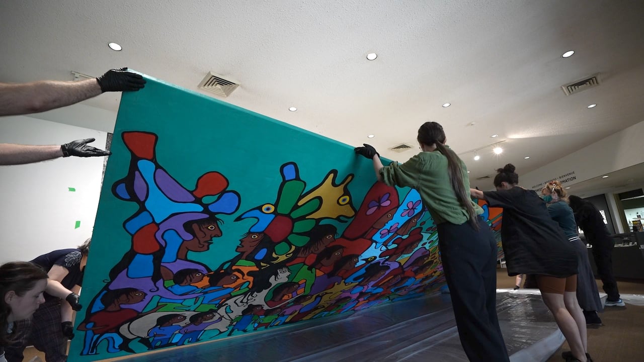Gallery staff mount the artwork and prepare to hang it for the public to view.