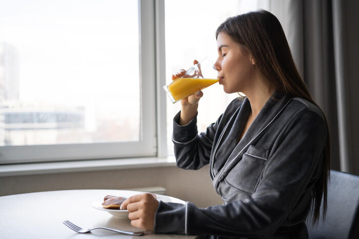 A woman drinks orange juice by a window, unaware of potential serious issues professionals treated that seemed innocent.