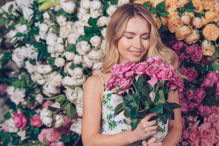 A woman happily smells a bouquet of pink roses, illustrating the seeming innocence of serious medical issues.