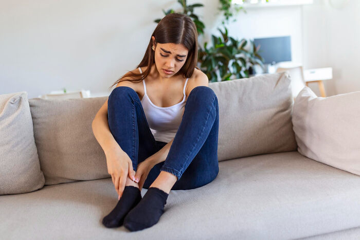 A young woman sits slumped on a couch, appearing distressed, illustrating serious issues and how they start innocent.