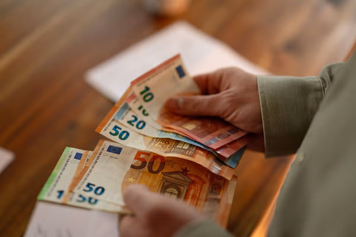 Close up of hands counting euro banknotes while planning household expenses and reviewing financial obligations.
