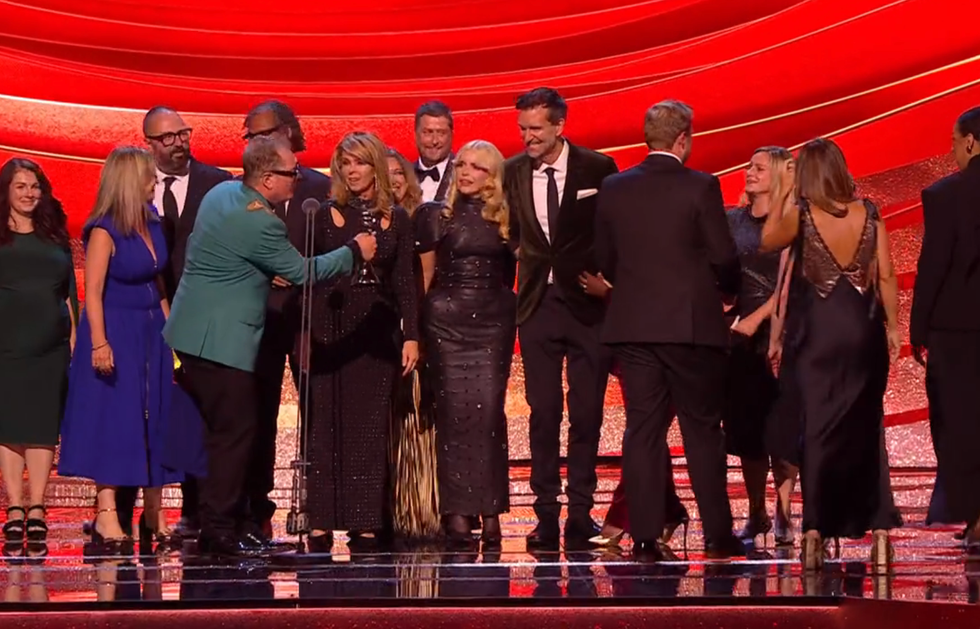 group of people on stage with award in front of a red backdrop group of people on stage with award in front of a red backdrop