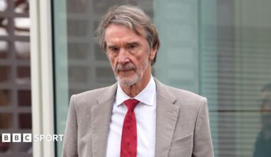 Sir Jim Ratcliffe in light-coloured smart jacket, white shirt and red tie