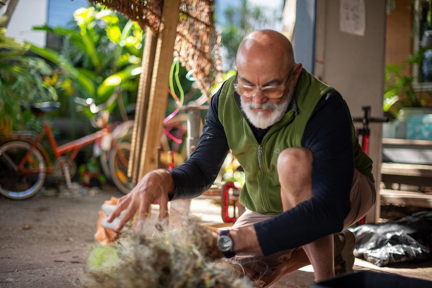 A man kneels among a tangle of discarded fishing line.