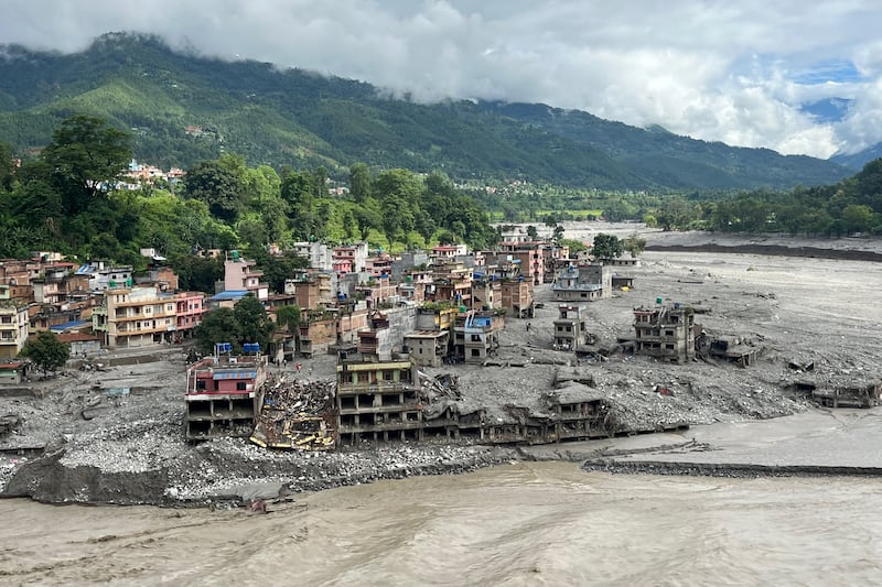 A torrent of muddy water surges past houses and through the Trishuli River in the aftermath of flash floods in Nepal's Nuwakot district. Photograph: Arun Sankar/AFP via Getty Images