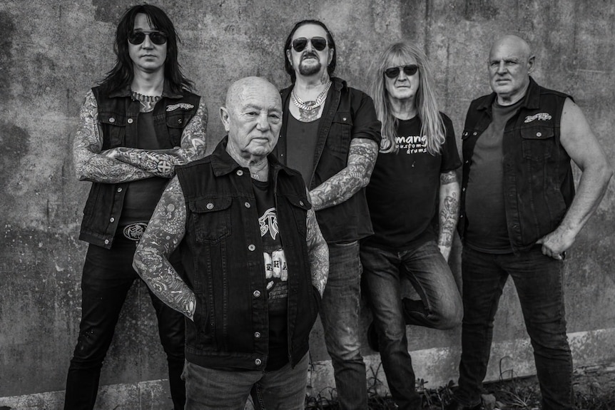 A black and white photo of five men, mostly with a lot of tattoos.