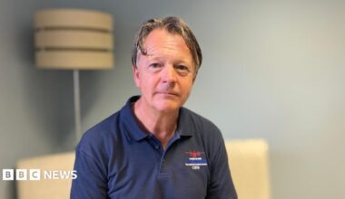 A man with grey hair wearing a navy blue polo shirt
