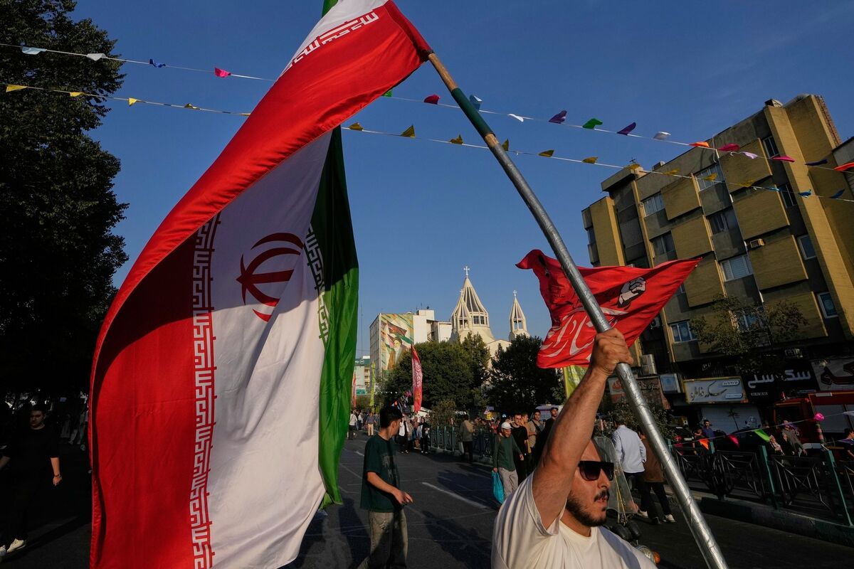 A man holds an Iranian flag during a street celebration marking Prophet Muhammad's birthday, with St. Sarkis Armenian Cathedral in the background, in Tehran, Sunday, Aug. 30, 2026. (AP Photo/Vahid Salemi)