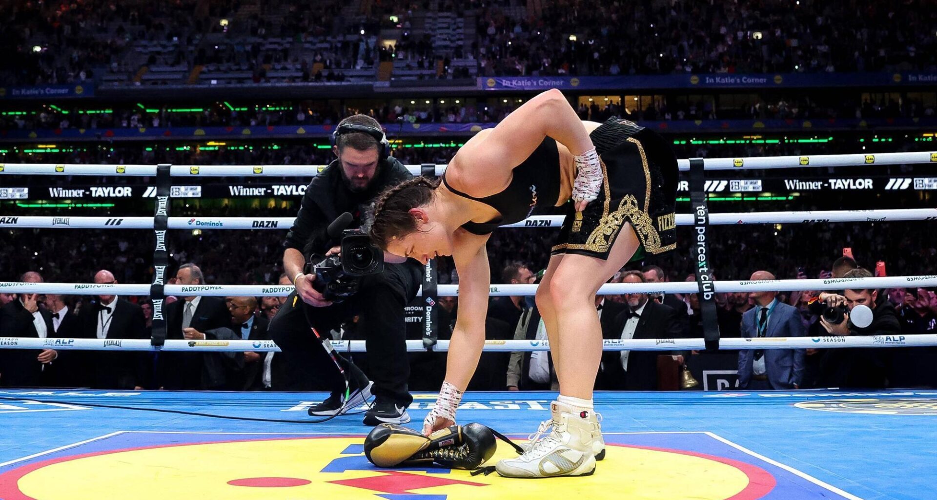 LAYING A GLOVE: Katie Taylor lays her boxing gloves on the canvas for the final time to signify her retirement after victory Saturday night at Croke Park. Pic: Gary Carr, Inpho