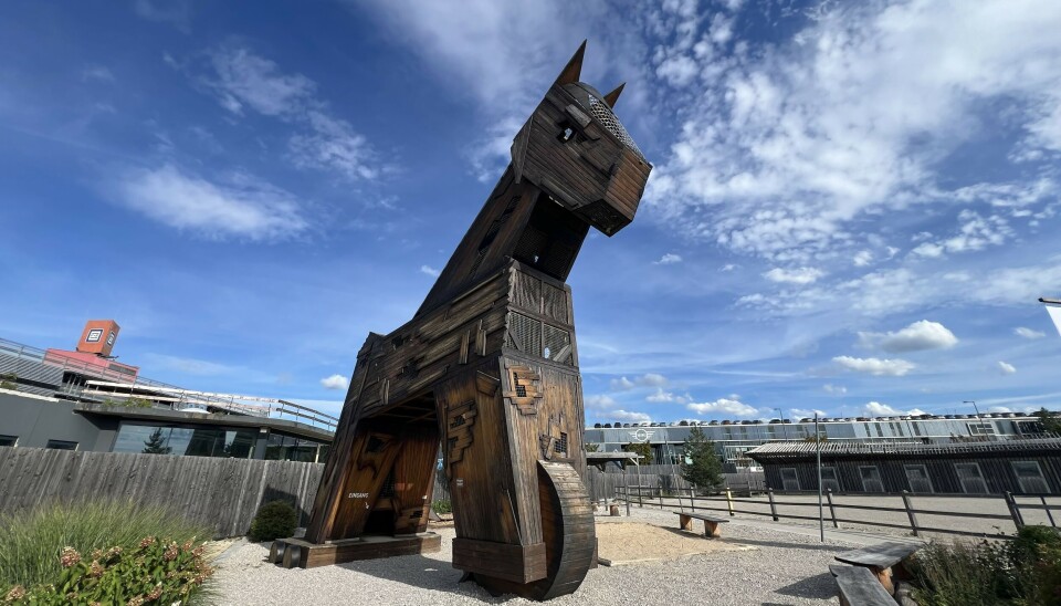 Large wooden horse sculpture outdoors beneath a partly cloudy sky.