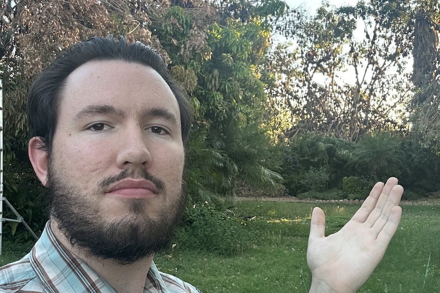 Aaron Gray points towards trees filled with flying foxes behind his Sunset home.