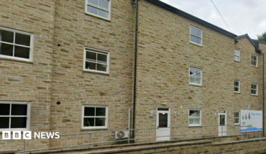 A large sandstone brick building with a white sign reading Pine House.