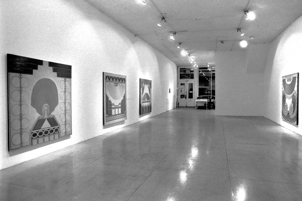 Art gallery interior featuring abstract paintings on white walls with polished concrete flooring.