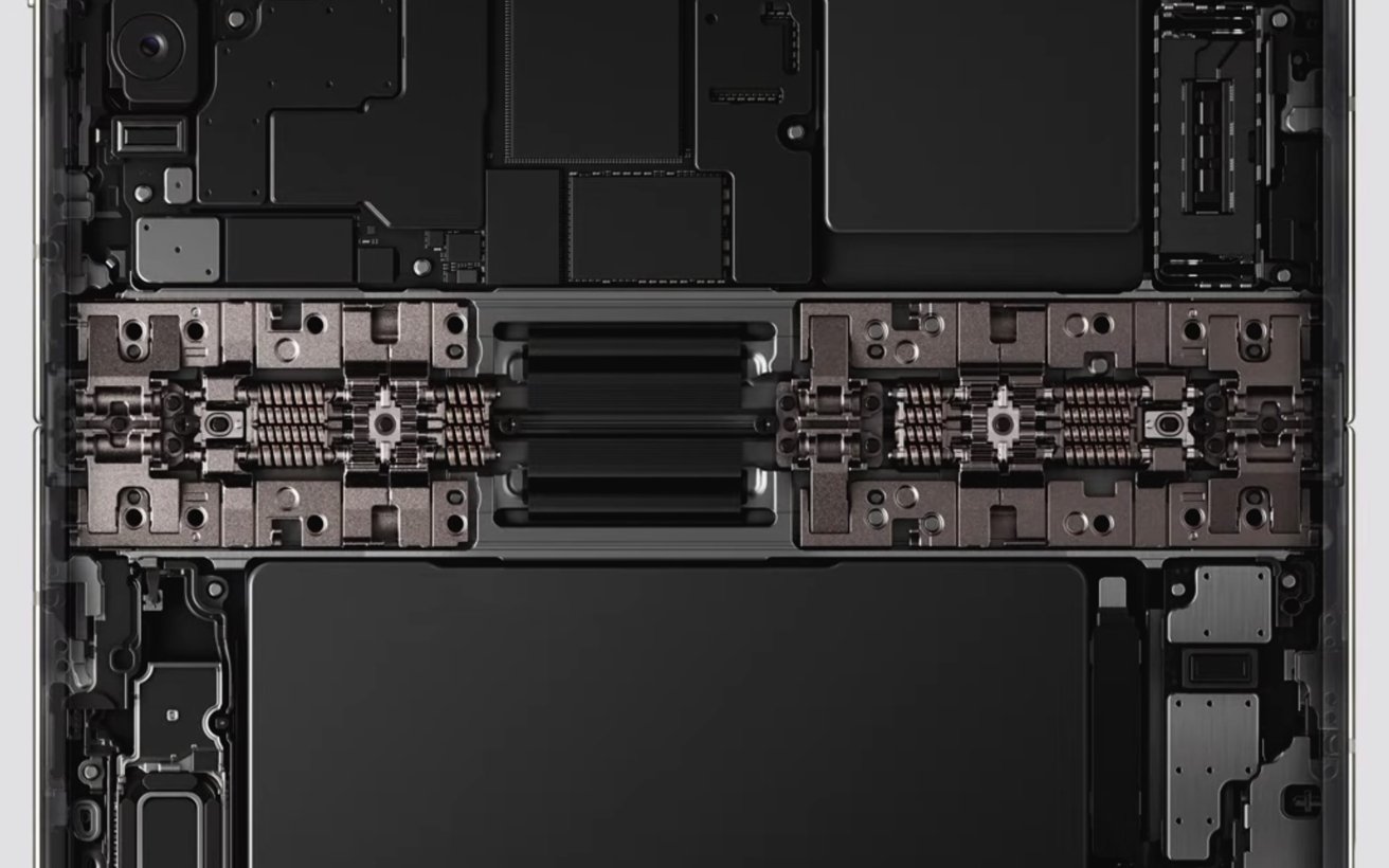 Internal view of a laptop showing symmetrical components, including a central hinge mechanism, battery cells, and circuit boards arranged in a clean, rectangular, industrial layout