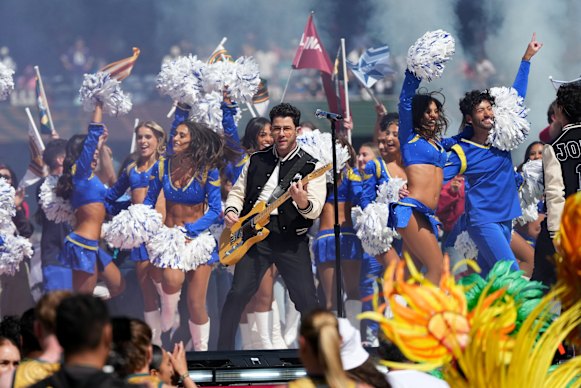 Nick Jonas shreds while the cheerleaders cheerlead.