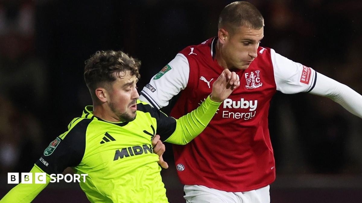 Rhys Norrington-Davies in a bright green Sheffield United away kit is down on his haunches after scoring an own goal