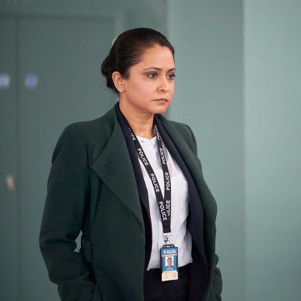 person with dark hair in a police lanyard stands in an office hallway. person with dark hair in a police lanyard stands in an office hallway.