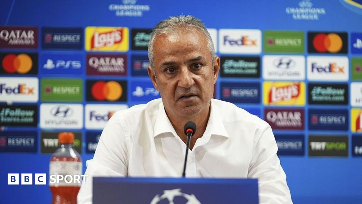 Ismail Kartal, pictured in a white shirt sitting behind a microphone and in front of a blue board covered in colourful sponsor logos
