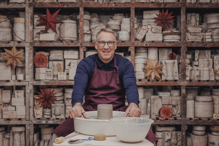 Paul Merson sat down at a potting studio smiling as he looks up ahead.