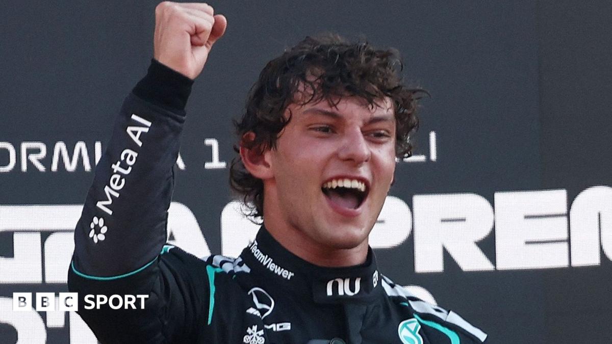 Kimi Antonelli smiles and clenches his right fist in celebration on the podium after winning the Italian Grand Prix