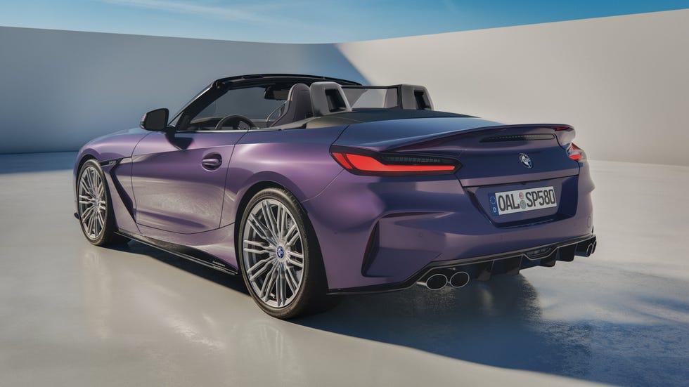 Purple convertible sports car parked in a modern setting with a clear blue sky. Purple convertible sports car parked in a modern setting with a clear blue sky.