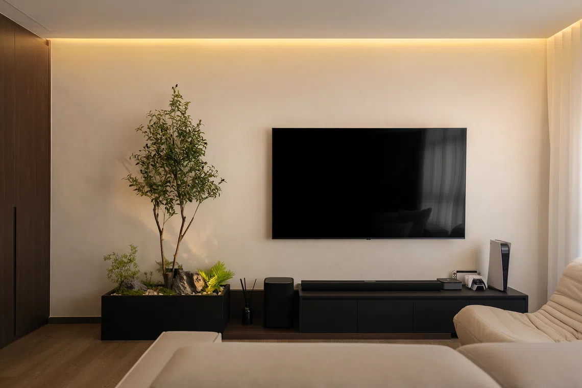 The TV console has a built-in space for the couple’s plants, with rocks and pebbles that evoke a Japanese Zen garden.