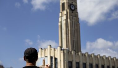 Man in front of a clock tower, painting that clock tower on an easel