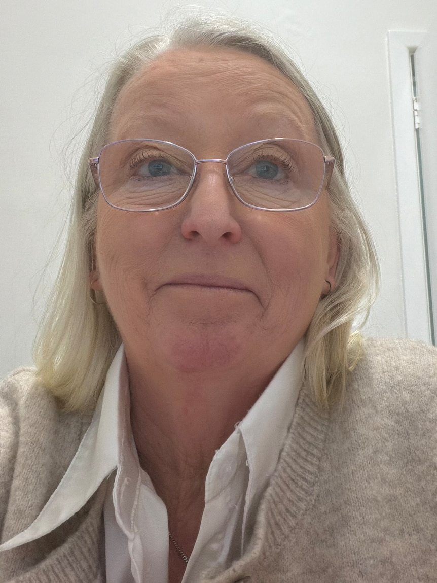 woman with white hair and glasses smiles at the camera