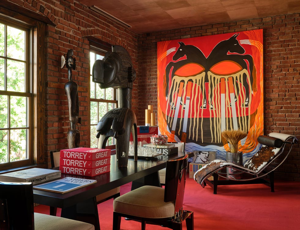 Interior view of a room featuring brick walls, artistic decor, a striking painting, and modern furniture elements.