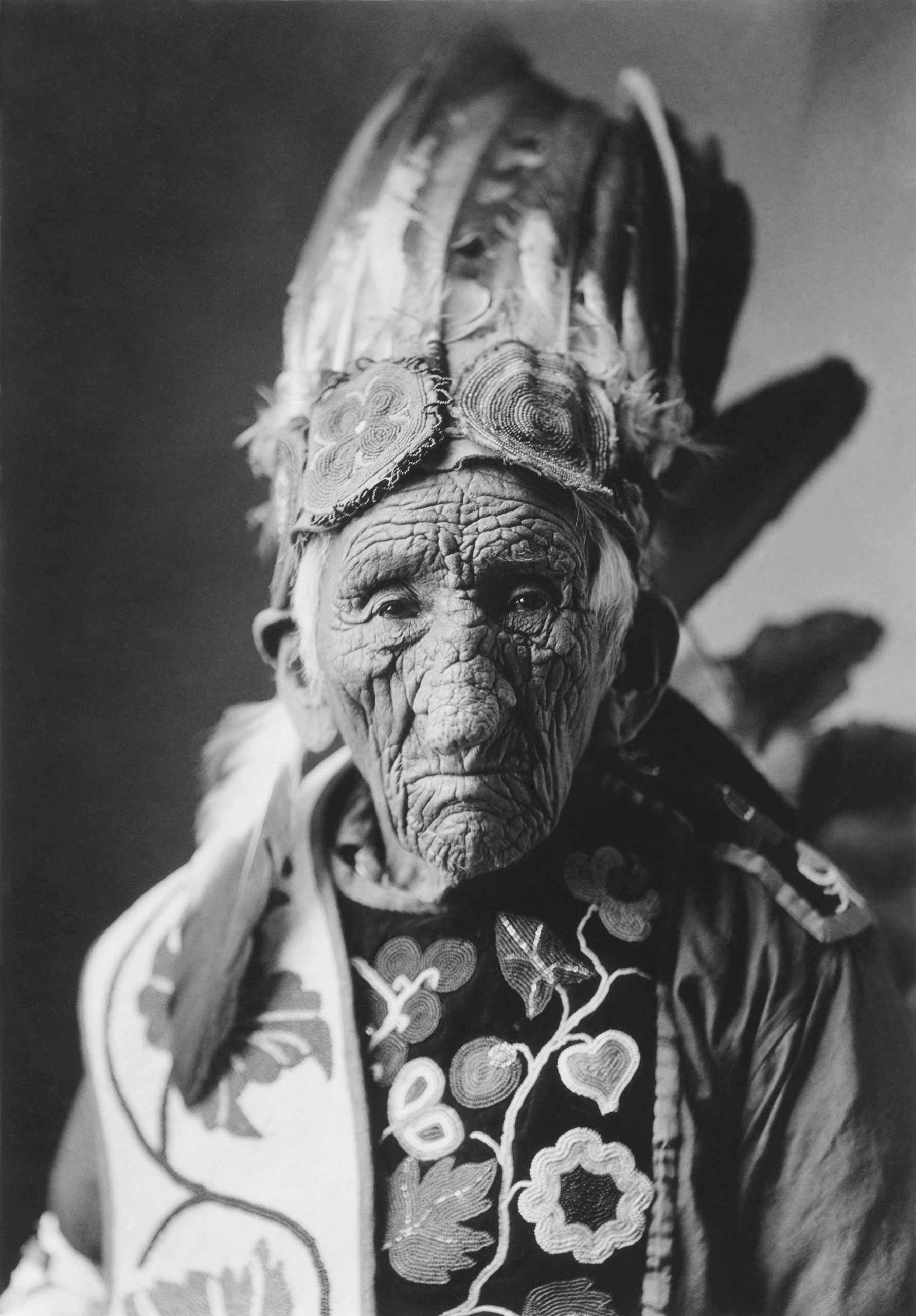 A black-and-white portrait of an elderly Chippewa chief in an elaborately beaded and feathered headdress and jacket.