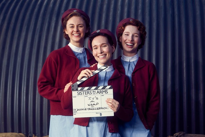 Ellie Mckay as Olive Dobbs, Liv Andrusier as Marianne Siegler and Lizzie Back as Sybil Maxted in Call the Midwife: Sisters in Arms, holding a clapperboard.