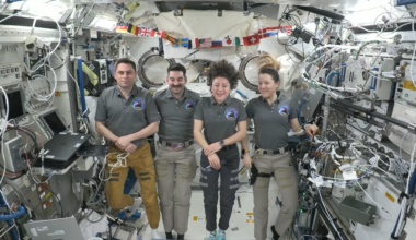 four people float in a space station module.