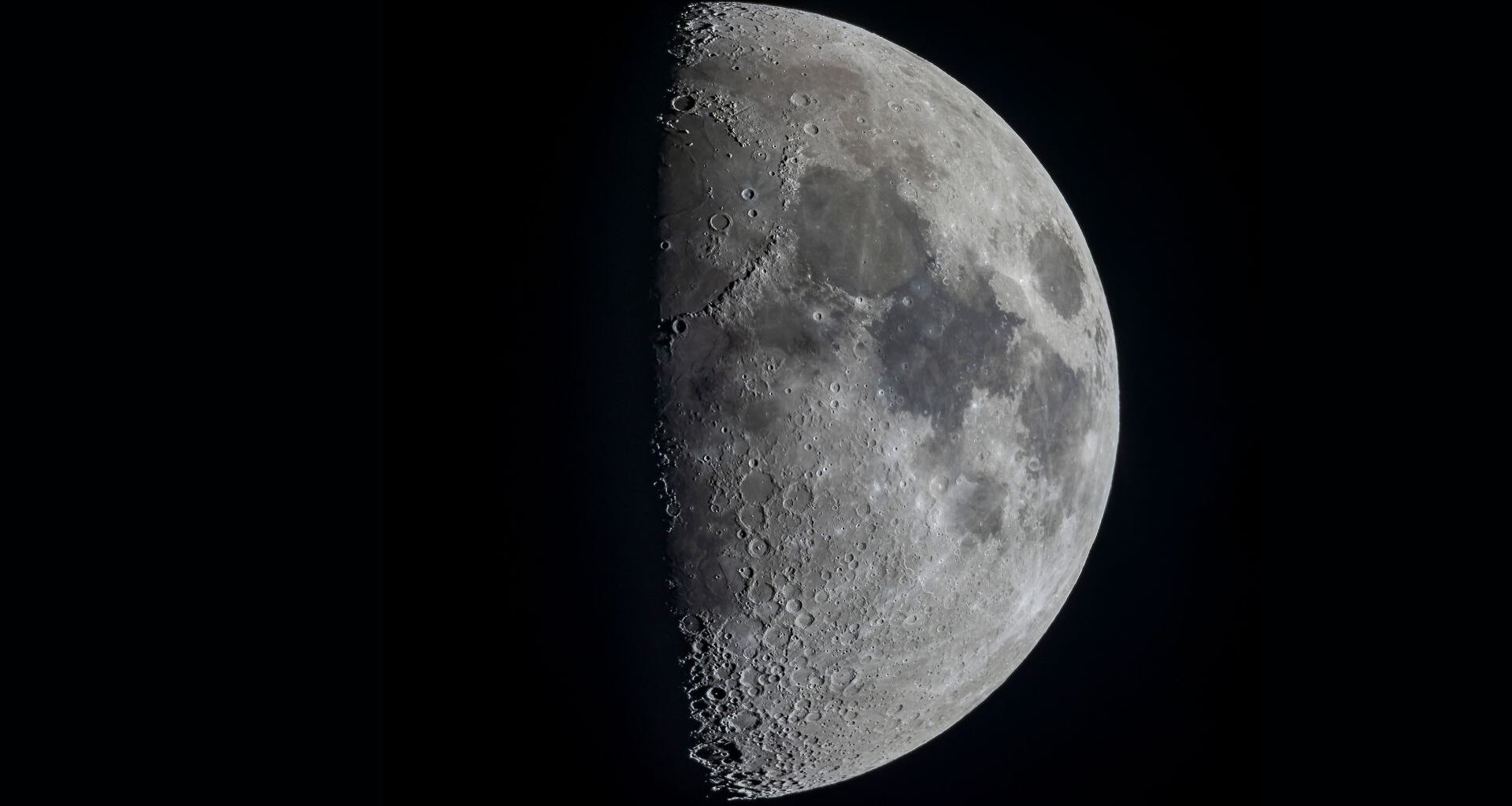 A half lit moon is shown in a black sky