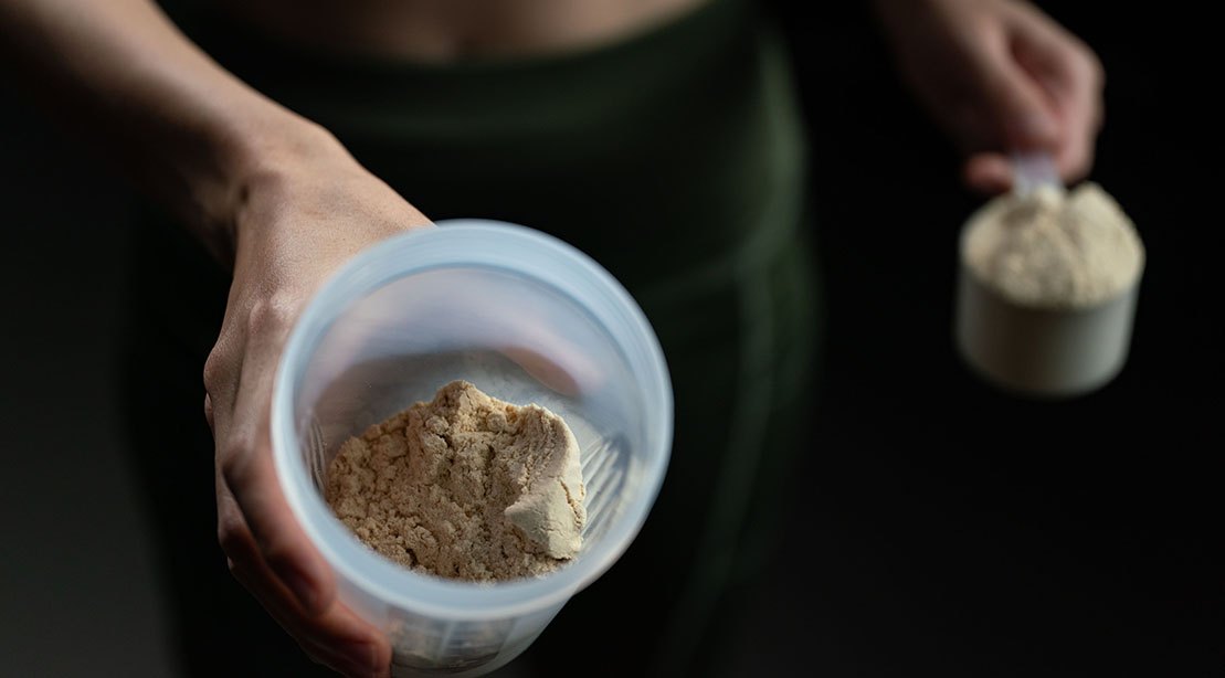 Fit woman using creatine powder supplement as part of her workout routine