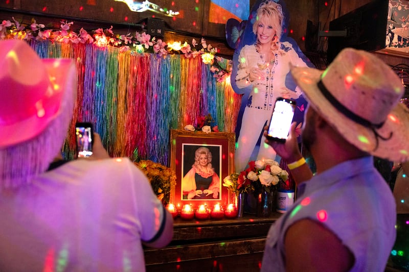 People take photos of a Dolly Parton memorial before a tribute drag show at Mary’s in Atlanta, Georgia. Photograph: Kendrick Brinson/The New York Times
                      